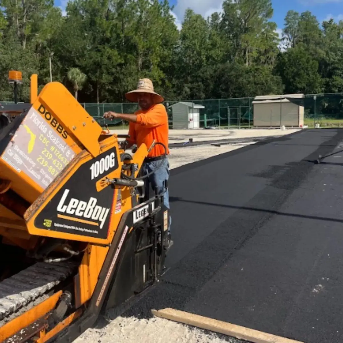 Florida Sealcoat and Striping crew laying fresh asphalt with a paver during a commercial paving job in Southwest Florida