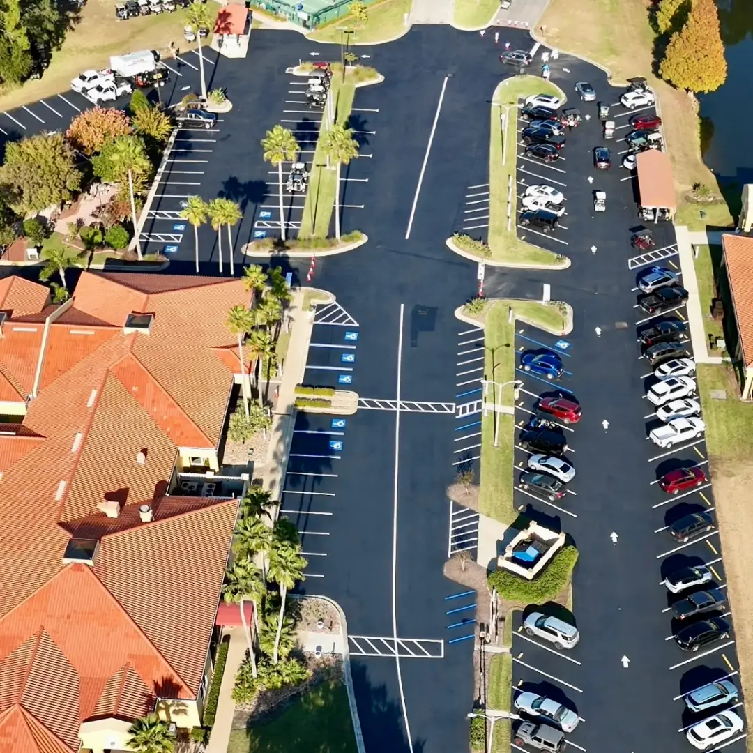 The same community parking lot after Florida Sealcoat and Striping completed full sealcoating and striping, with fresh black surface, ADA accessible stalls, directional arrows, and crosswalk markings in Southwest Florida