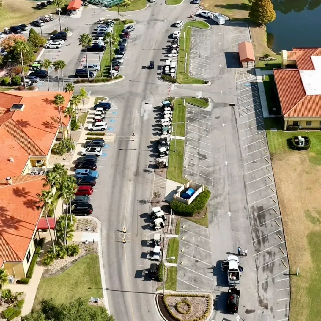 Community parking lot before sealcoating, showing worn gray asphalt with Florida Sealcoat and Striping crews on site preparing for the job in Southwest Florida