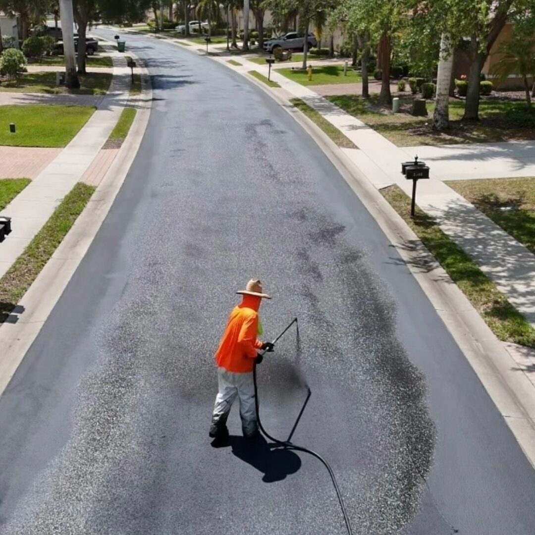 Florida Sealcoat and Striping worker applying sealcoat to a community road in Southwest Florida