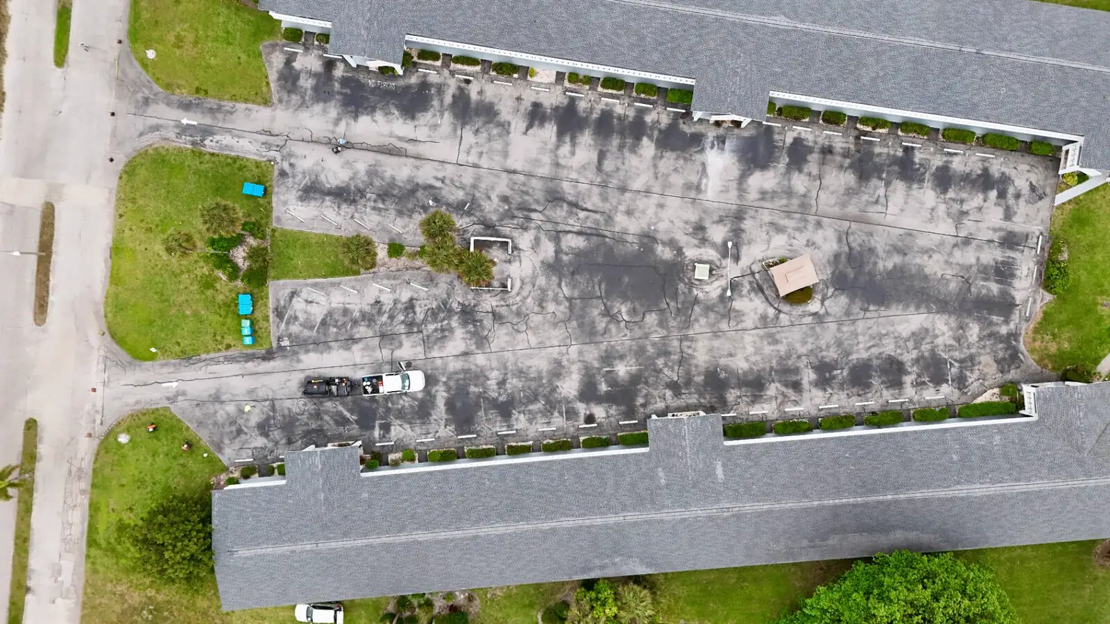 Condo community parking lot before sealcoating, showing a faded gray surface with extensive cracking in Southwest Florida
