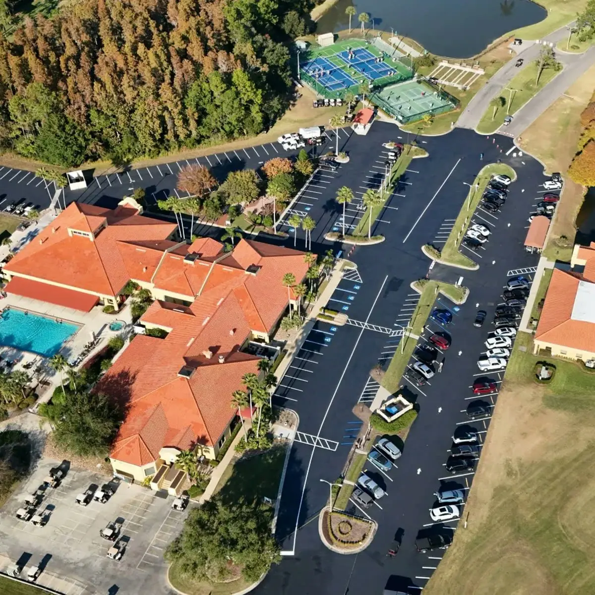 Aerial view of a freshly sealcoated country club parking lot with clubhouse pool and recreation courts in Southwest Florida by Florida Sealcoat and Striping