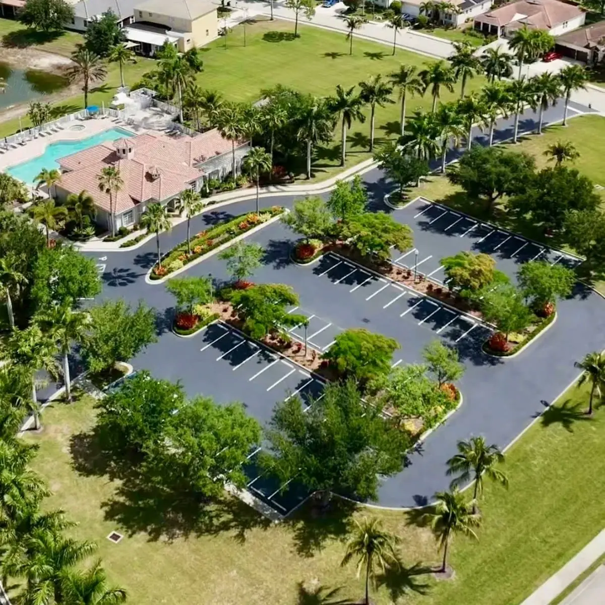 Freshly sealcoated HOA community parking lot with clubhouse pool and landscaped islands in Bonita Springs Florida by Florida Sealcoat and Striping