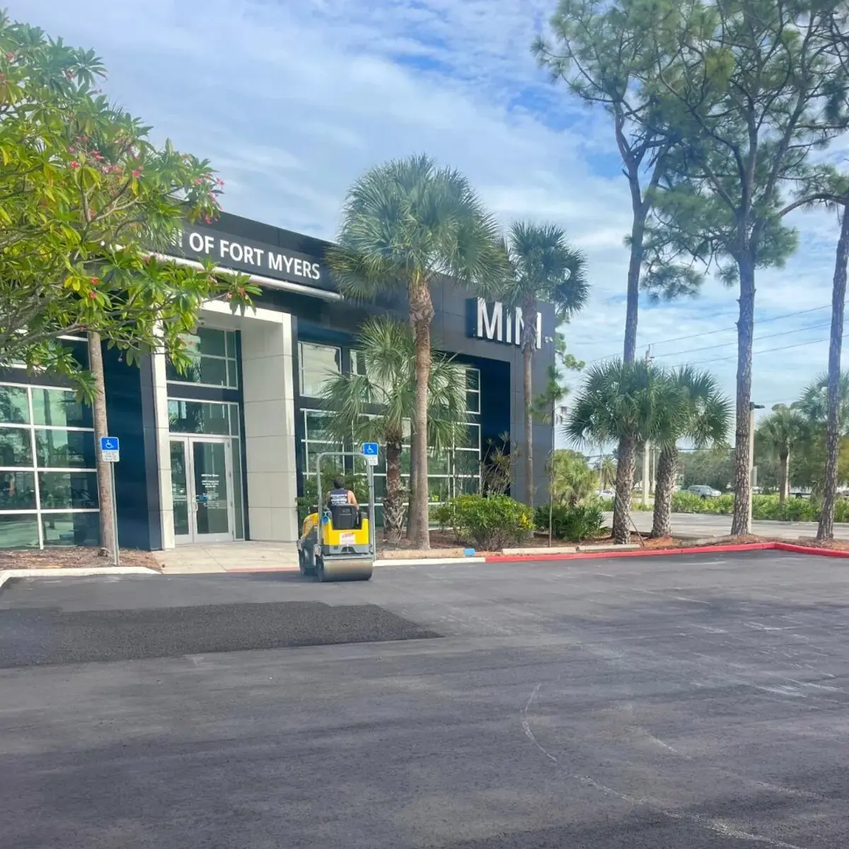 Roller compacting fresh asphalt at the MINI of Fort Myers auto dealership in Fort Myers Florida by Florida Sealcoat and Striping