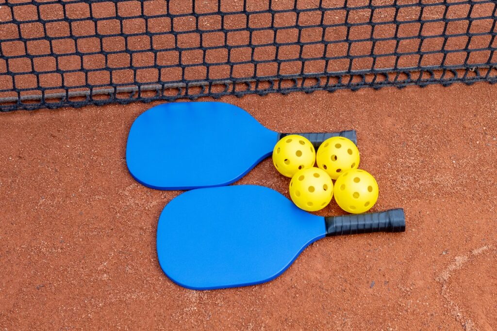 three paddles and three balls on a tennis court