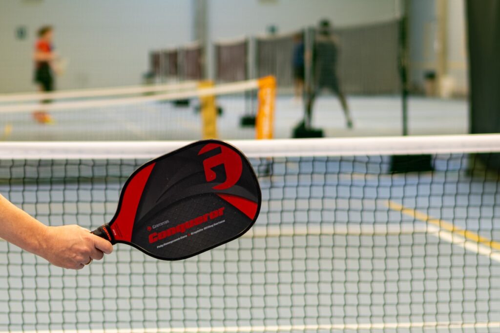 a person holding a ping pong paddle over a net