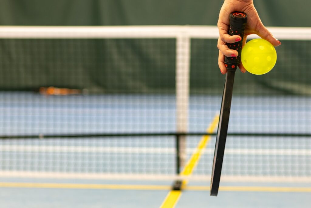 a person holding a pickleball and a racket
